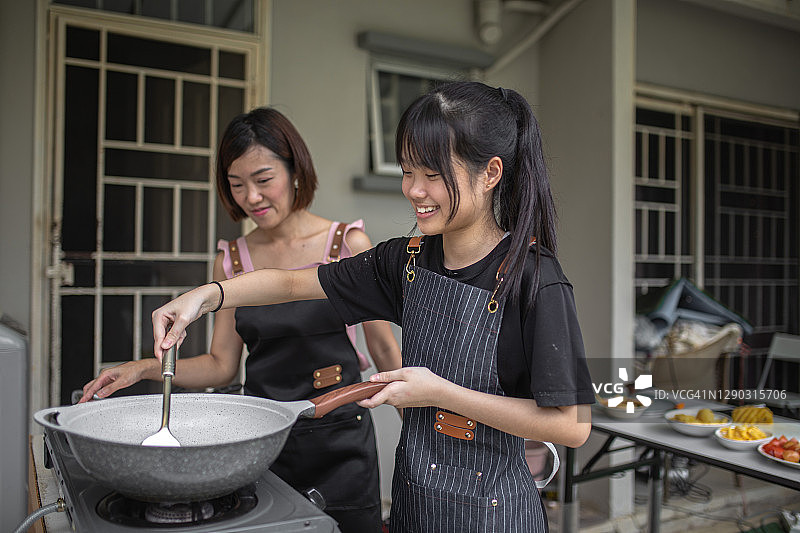 亚裔华人母亲和女儿在后院厨房准备食物。女儿在向母亲学习图片素材