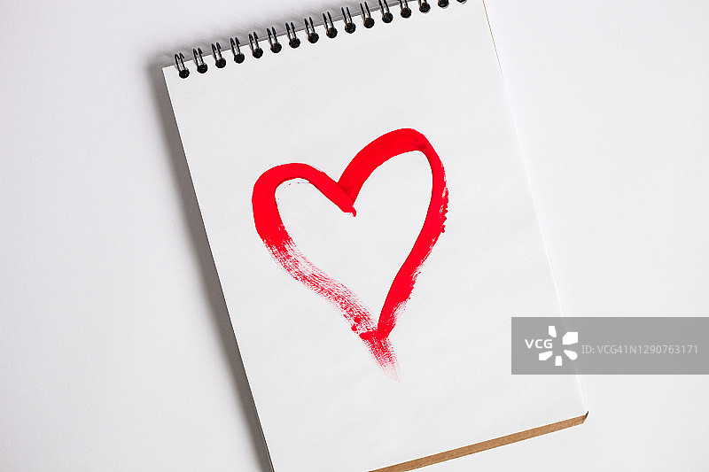 用红漆画的心的便条本，俯视图，平躺，情人节贺卡。礼物和爱的概念。图片素材