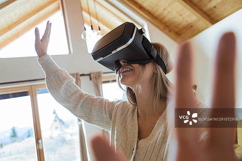 女人戴着虚拟现实眼镜在家玩图片素材