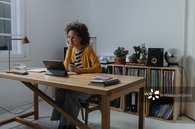 深夜在家工作:一个年轻的非洲裔美国妇女坐在她的家庭办公室里使用数字平板电脑图片素材