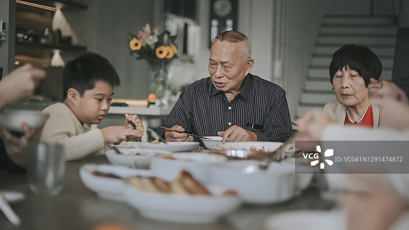亚洲华人家庭在餐桌上吃传统菜肴的年夜饭图片素材