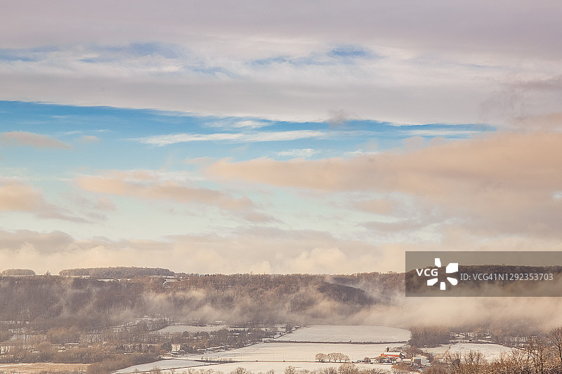 空中冬季景观与云彩和冬季天空，白雪覆盖的山丘和红谷仓图片素材