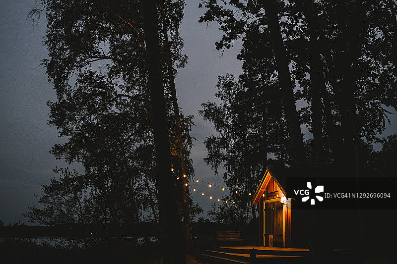 夕阳西下时，农舍旁的树上挂着灯光图片素材