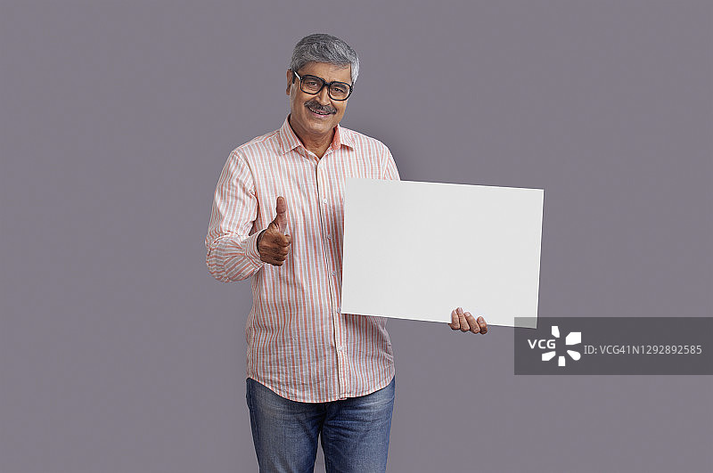 一位长者指着手里的一张白色方形布告。图片素材