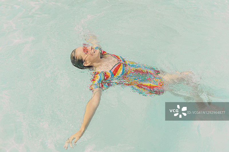 穿着衣服的女人漂浮在游泳池的水面上图片素材