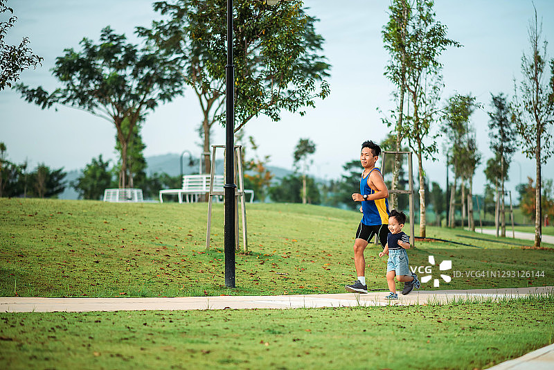 亚洲华人父亲和他的儿子在周末早上一起在公园里跑步图片素材