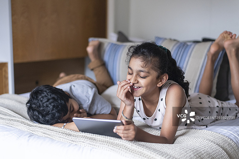 小学年龄的印度裔兄弟姐妹在平板电脑上玩屏幕时间图片素材