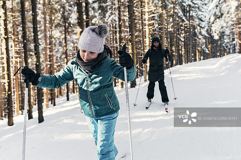 小女孩和家人在阳光明媚的雪地里滑雪图片素材