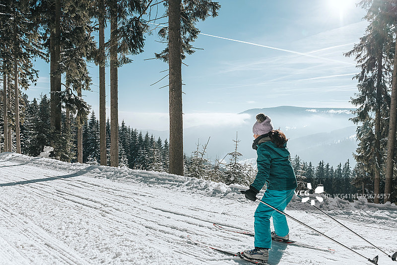 小女孩在阳光明媚的雪地里滑雪图片素材