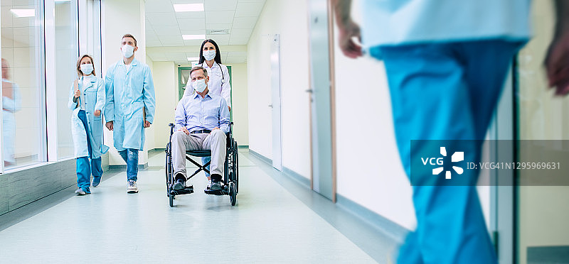 生病的老人在轮椅上戴着安全防护面具，一个自信的医生在医院运送时戴着医用面具。图片素材