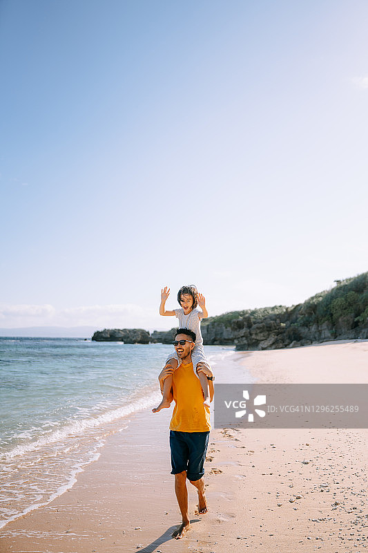 快乐的父亲背着小女儿在海滩上图片素材