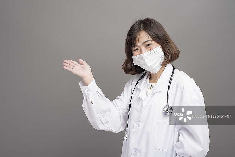 年轻自信的女医生戴着外科口罩在灰色背景的工作室图片素材