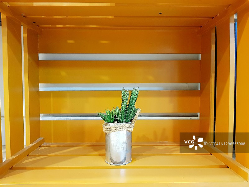 黄色装饰架子上有植物的小花盆。图片素材