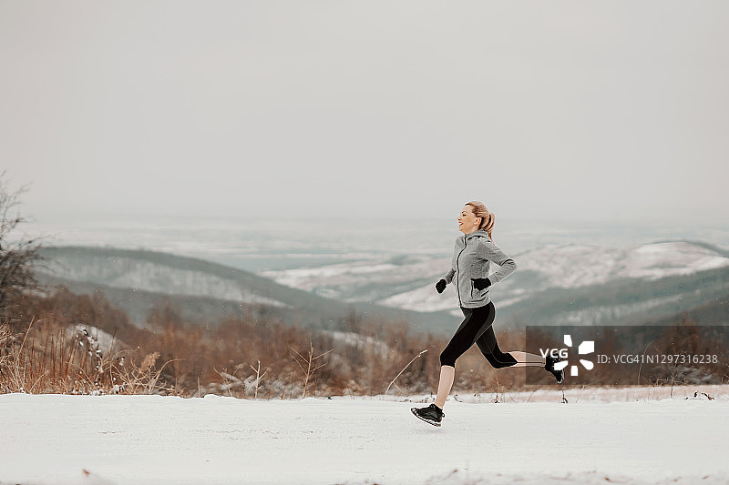 冬季，女运动员在雪道上快速奔跑。健康的生活方式，冬天健身，寒冷的天气图片素材