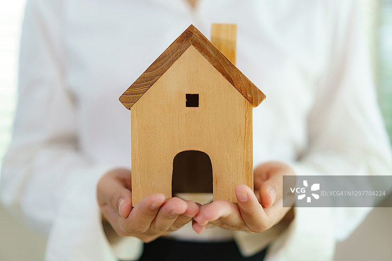 房地产经纪人手里拿着房子模型。按揭贷款的批准，住房贷款和保险的概念。图片素材