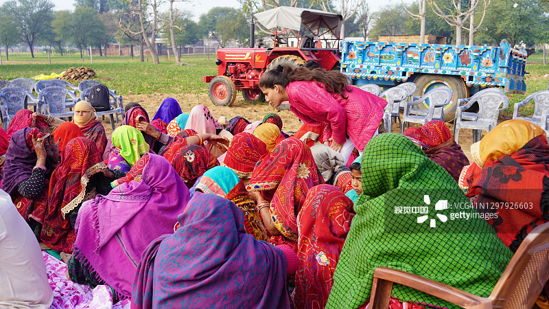 不同的印度妇女穿着五颜六色的衣服坐在地上，参加家庭成立仪式。图片素材
