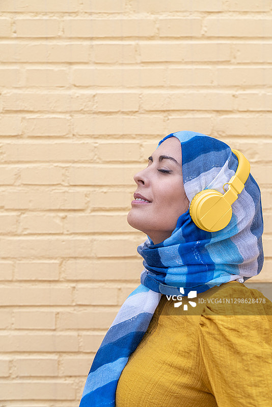 穆斯林妇女使用无线耳机听音乐图片素材