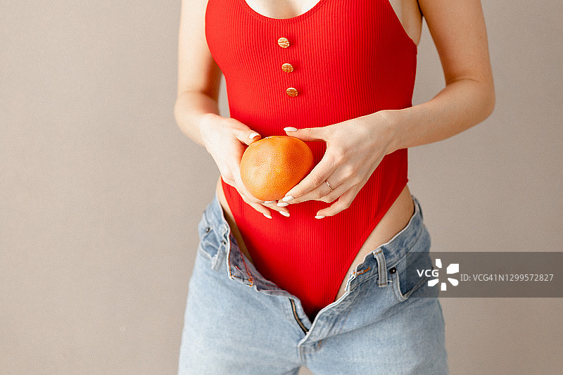 一个女人拿着葡萄柚靠近她的肚子图片素材