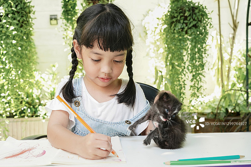 亚洲小女孩写作和花时间与她的猫图片素材