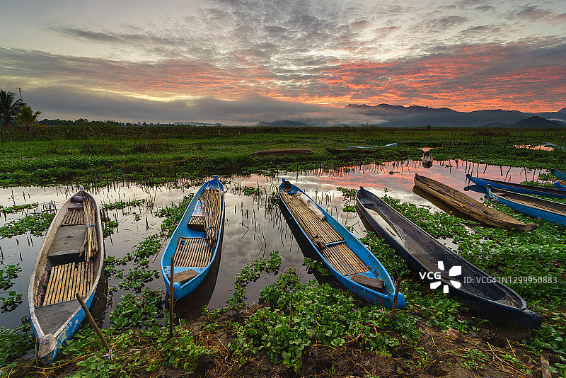 日落时分，印度尼西亚松巴哇的勒波湖上停泊着一排排渔船图片素材