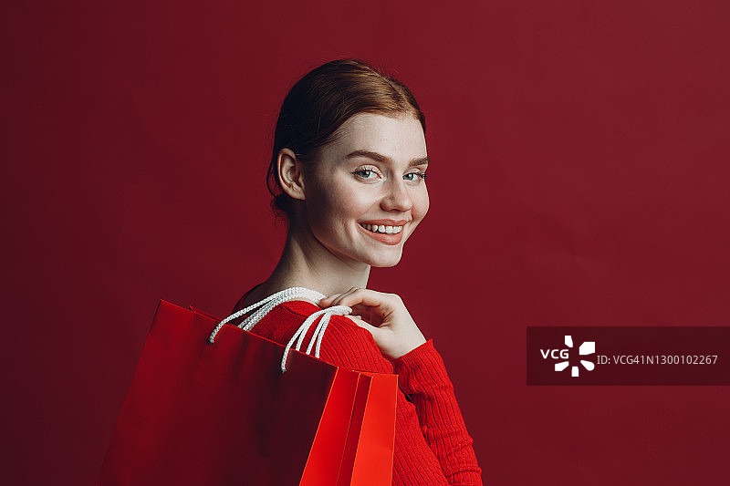 漂亮女人微笑肖像与纸红色购物袋。黑色星期五和促销概念。图片素材