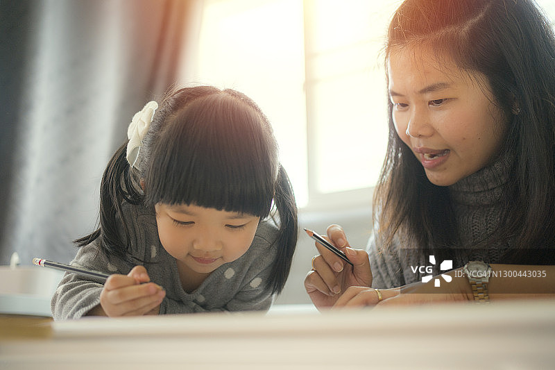 幸福的家庭时刻亚洲年轻的成年母亲教她的女儿在家里做作业图片素材