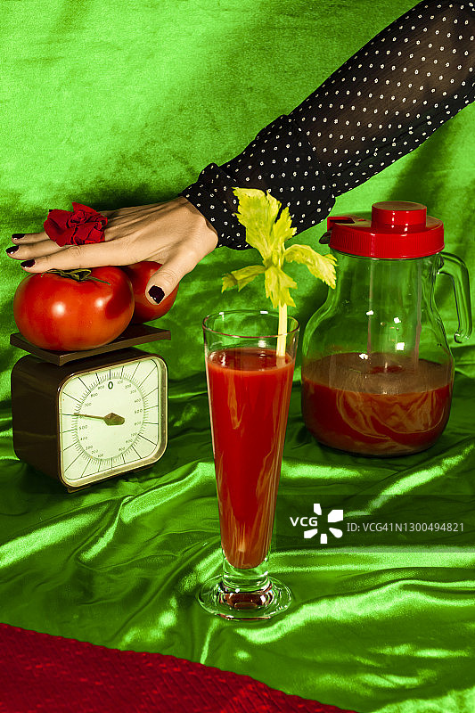 手与西红柿的妇女体重秤上的果汁对绿色织物图片素材
