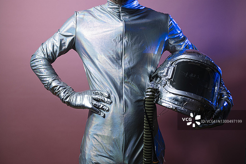 男性宇航员手握太空头盔，站在有色背景下图片素材