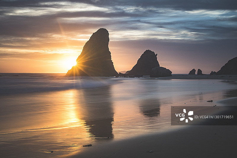 戏剧性的金色早晨的日出反射了海岸岩石形成的潮汐图片素材