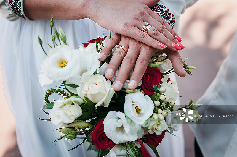 新婚夫妇的手和婚戒在婚礼花束图片素材