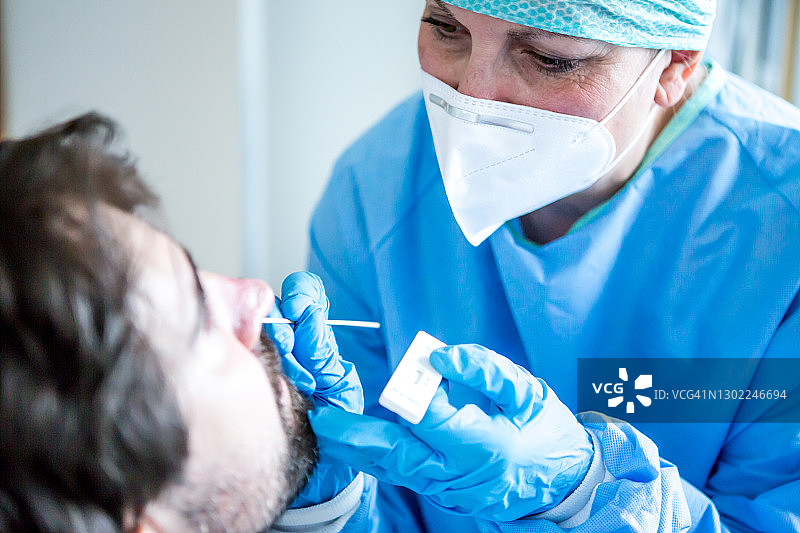 流行病-身着防护服的医务人员从病人的鼻子中提取样本。图片素材