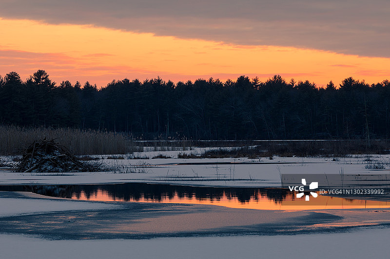 五彩缤纷的夕阳倒映在结冰的池塘上图片素材