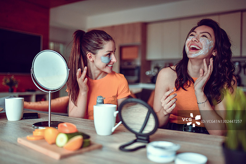可爱的女性帮助室友在脸上涂抹护肤霜图片素材