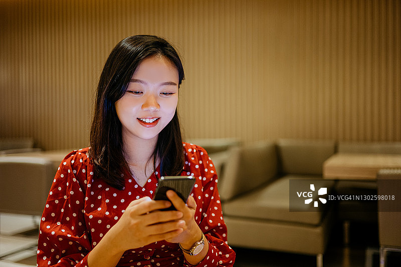 一名年轻的亚洲女子在餐厅用智能手机图片素材
