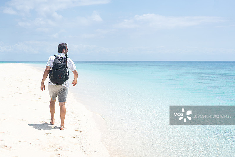 徒步在热带沙滩上的背包客图片素材