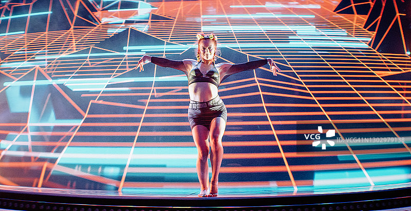 在投影背景下表演的现代女舞者。里面是超现实的数字景观，紫色的山脉和霓虹灯图片素材