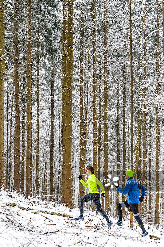 男女运动员在冬季的森林小道上奔跑图片素材