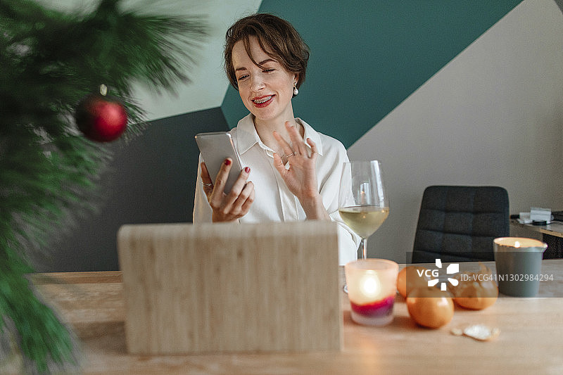 圣诞节期间，在家里通过智能手机进行视频通话的微笑女人图片素材