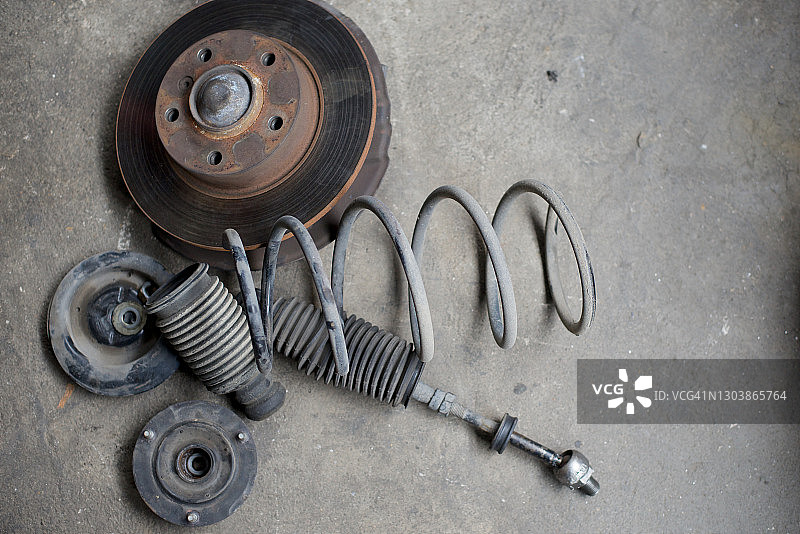 旧汽车的盘式刹车片、盘式弹簧和减震器，在车库修理汽车零件图片素材