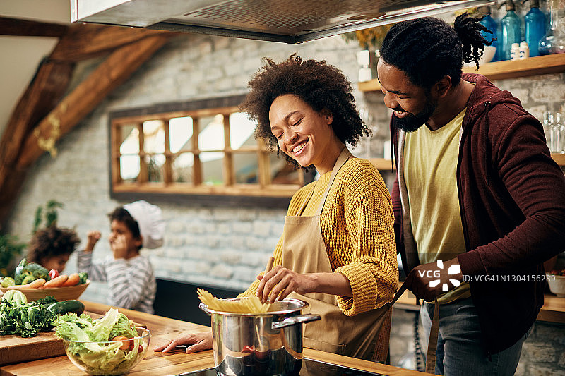快乐的非裔美国父母在厨房做饭。图片素材