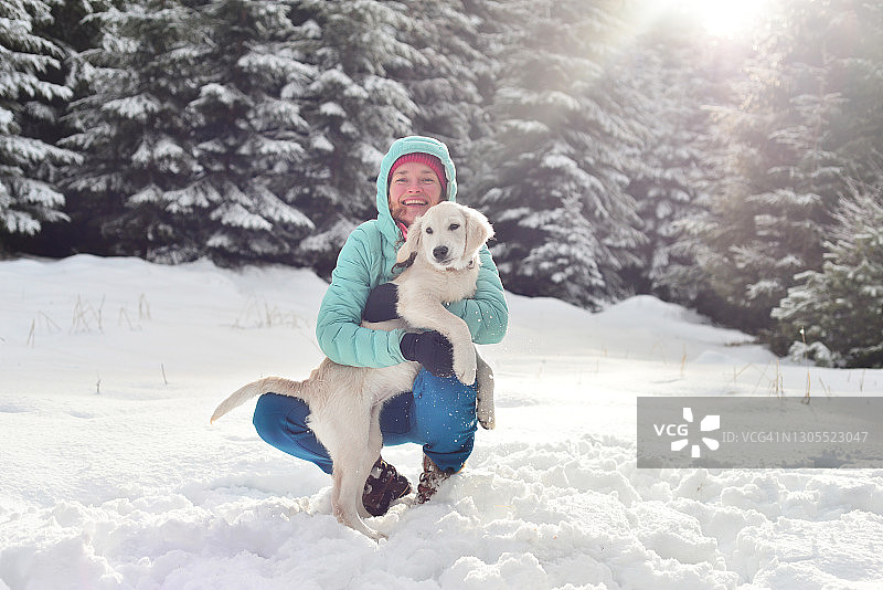一个年轻女子和她的金毛猎犬在雪中玩耍图片素材