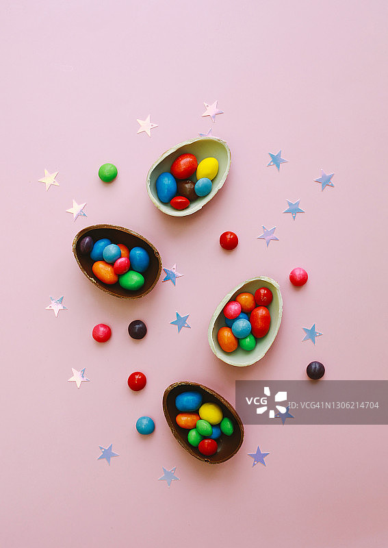 巧克力复活节彩蛋和彩色糖果在粉红色的背景。节日贺卡。图片素材