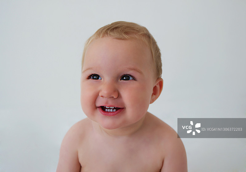 在白色背景上微笑的男婴的肖像图片素材
