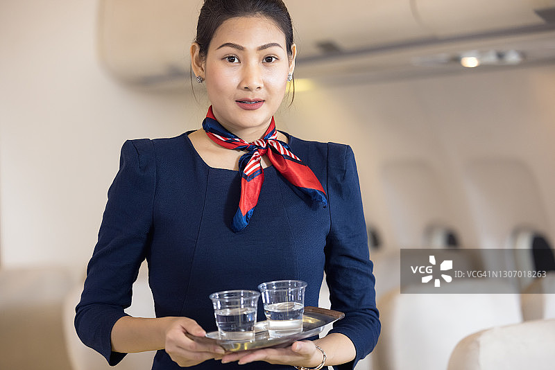 在飞机上，机组人员为乘客提供水。航空运输和旅游理念。图片素材