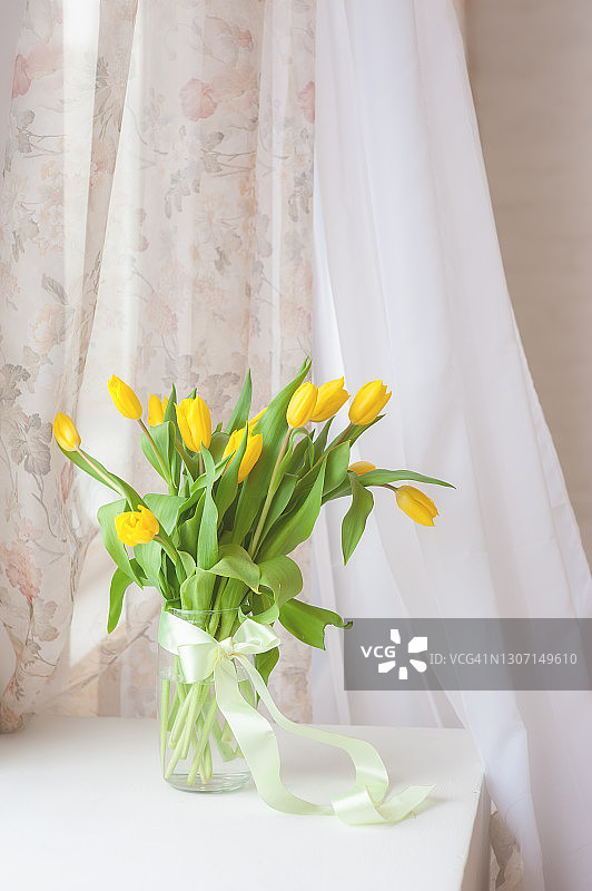 桌上的照片，玻璃花瓶里的黄色郁金香图片素材