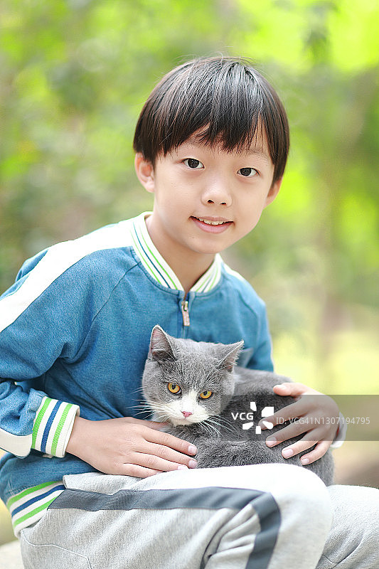 可爱的小男孩依偎着他的小猫。图片素材
