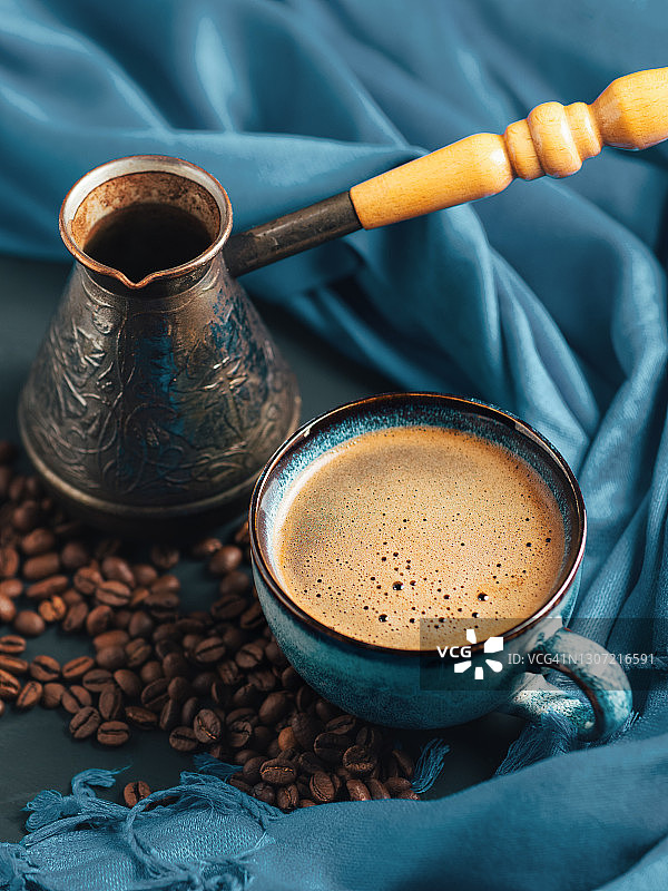 一杯芬芳的咖啡，烘培的咖啡豆。漂亮的蓝色杯子和耶兹瓦图片素材