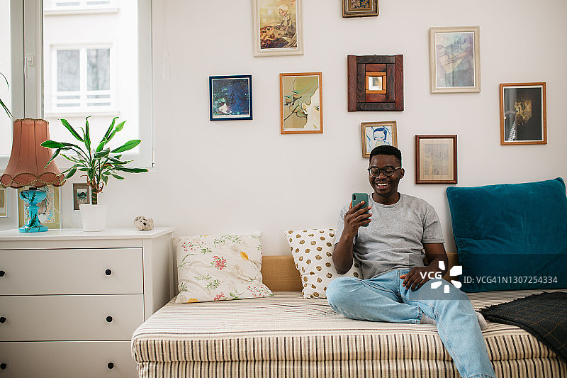 快乐的年轻非裔美国人在用智能手机图片素材