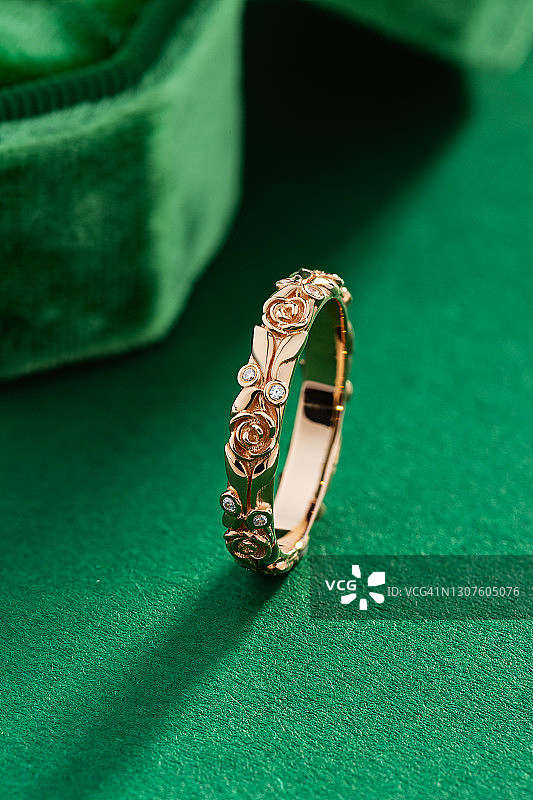玫瑰金戒指与钻石在花卉设计的绿色背景图片素材