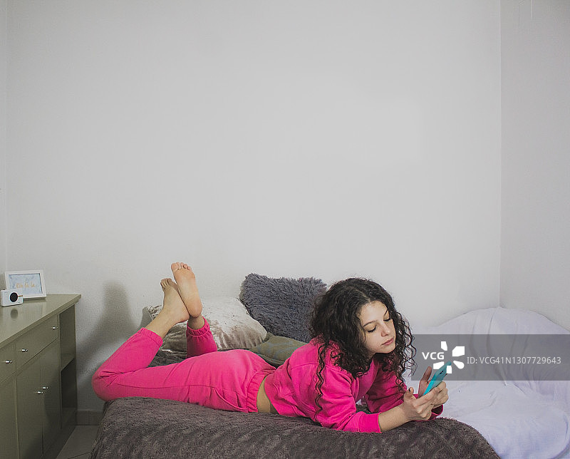 女人在床上用手机看社交媒体图片素材